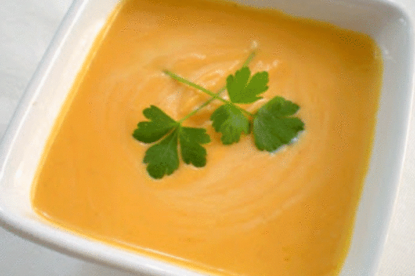 Sweet potato soup in a white bowl topped with herbs